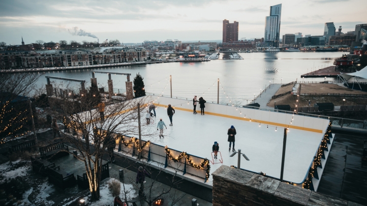 Experience festive cheer at Four Seasons Hotel Baltimore's Winter Village, featuring a rooftop skating rink, seasonal treats, cozy cabanas, and stunning harbor views.